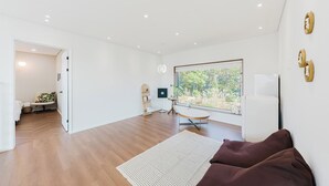 Una habitación amplia con un ventanal grande, un sofá, una mesita y una estantería.