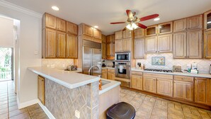 A kitchen with wooden cabinets, a stainless steel refrigerator, a microwave, and a stove. - Beautiful home with modern conveniences - close to the beach, dogs welcome (St. Simons Island)