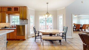 A spacious kitchen with wooden cabinets, a stainless steel dishwasher, and a large dining table with chairs. - Beautiful home with modern conveniences - close to the beach, dogs welcome (St. Simons Island)