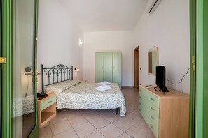 Ein Schlafzimmer mit Bett, Nachttisch, Kleiderschrank und Fernseher.