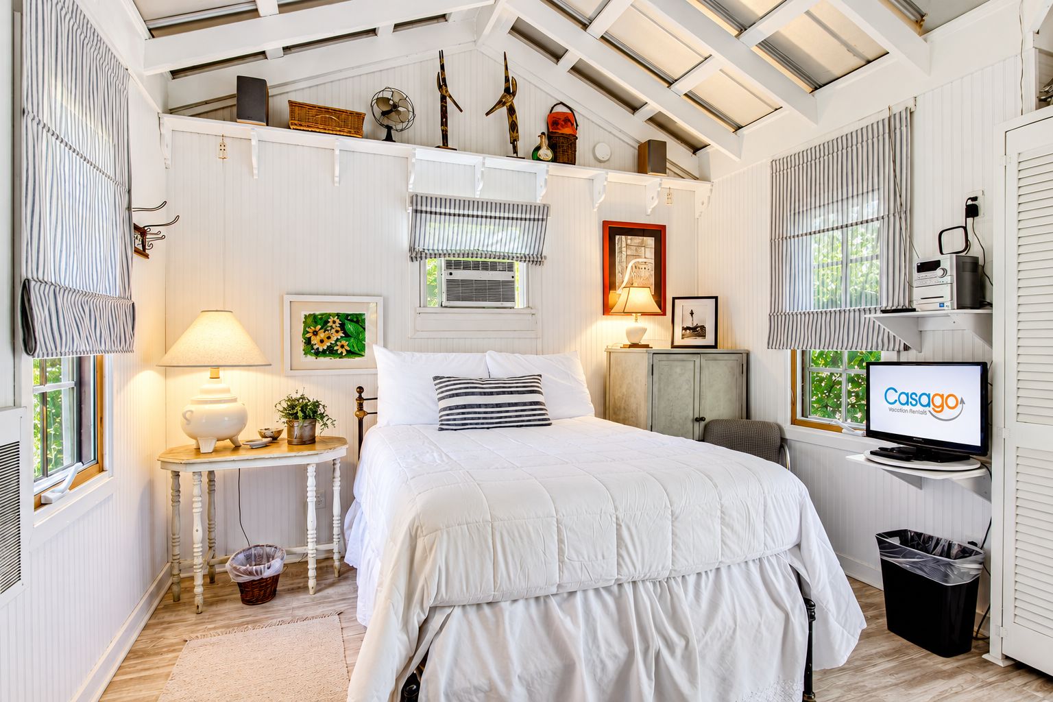 A bedroom with a bed, bedside tables, a lamp, a television, and a window with blinds.