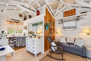 A cozy interior with a dining area, a seating area with a sofa and chair, and a bookshelf. - Charming Getaway w/ a Kitchenette & Free WiFi - Walk to the Beach (St. Simons Island)