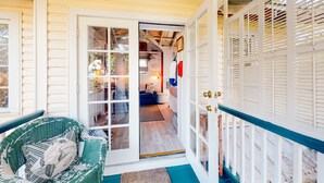 Un interior acogedor con una silla de mimbre, un cristalero que da a una sala de estar y una terraza de madera.