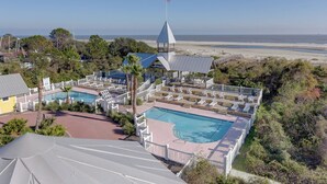 Ett semesterhotell med en swimmingpool, solstolar och utsikt över stranden.