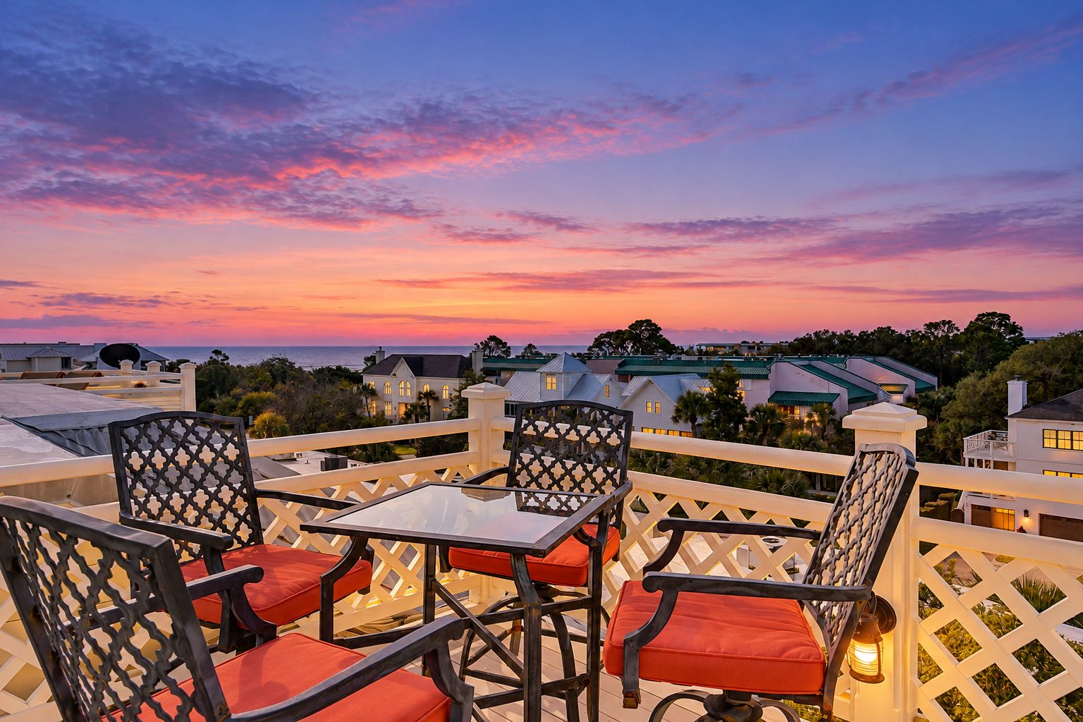 A terrace with outdoor seating and a view of the ocean at sunset.