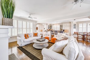Ein geräumiges Wohnzimmer mit einer weißen Sofagarnitur, einem Couchtisch und einem Essbereich mit Tisch und Stühlen.