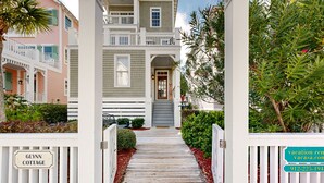 A wooden pathway leading to a house with a porch and a sign reading "GLYNN COTTAGE". - Luxury cottage with pools & multiple decks, 1/2 block to beach (St. Simons Island)