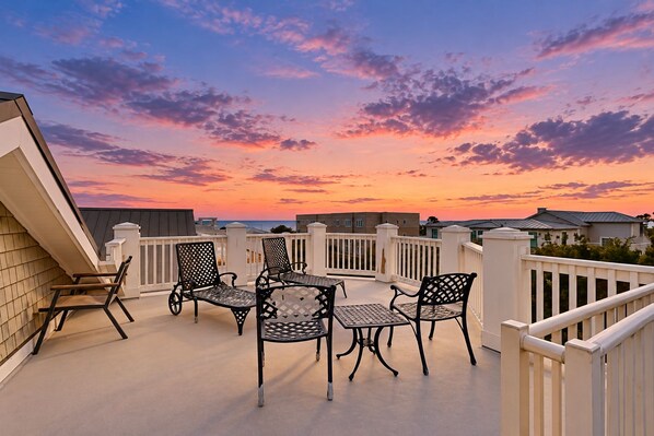 Ein Balkon mit Tisch und Stühlen, Geländer und Blick auf den Himmel.