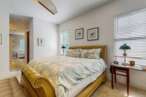 Une chambre à coucher avec un grand lit, une table de chevet avec une lampe et une fenêtre avec des stores.