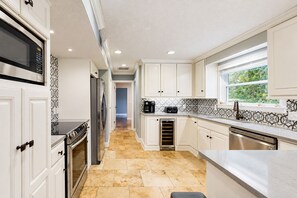 A modern kitchen with white cabinetry, stainless steel appliances, and a patterned backsplash. - Dog-friendly home with central AC, washer/dryer & spacious backyard - near beach (St. Simons Island)