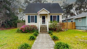 Une maison à deux étages avec un porche à l’avant, une clôture en bois et une pelouse bien entretenue.