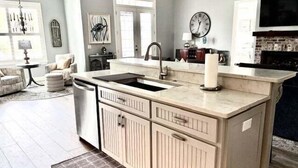 A kitchen with a central island, a sink, and a clock on the wall. - Golf course-view home near beaches with deck, porch, grill, streaming, W/D, & AC (St. Simons Island)