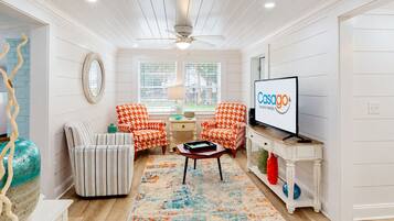 A modern living room with a television, two patterned armchairs, a coffee table, and a decorative rug.