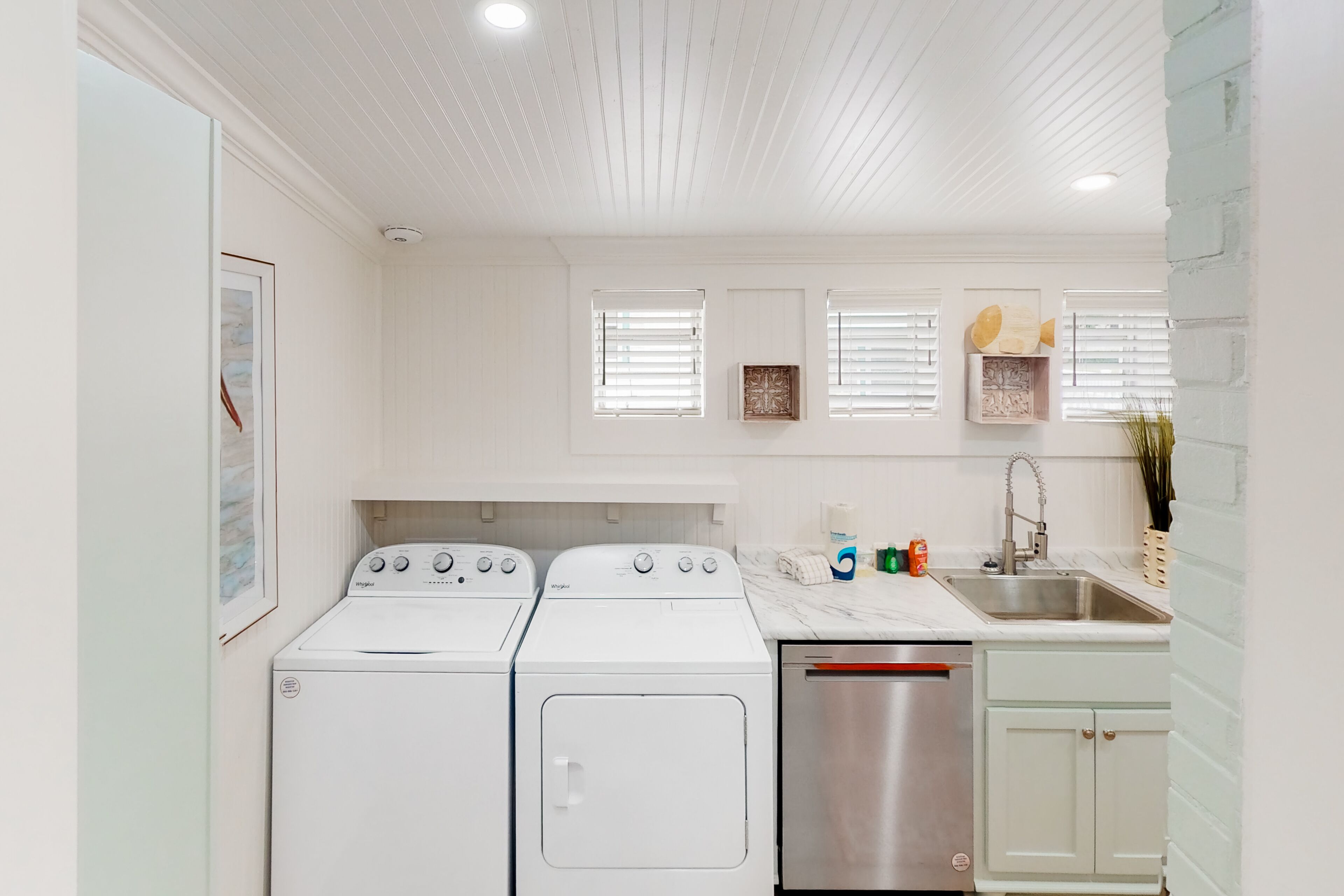 A laundry area with two front-loading washers and a stainless steel dryer.