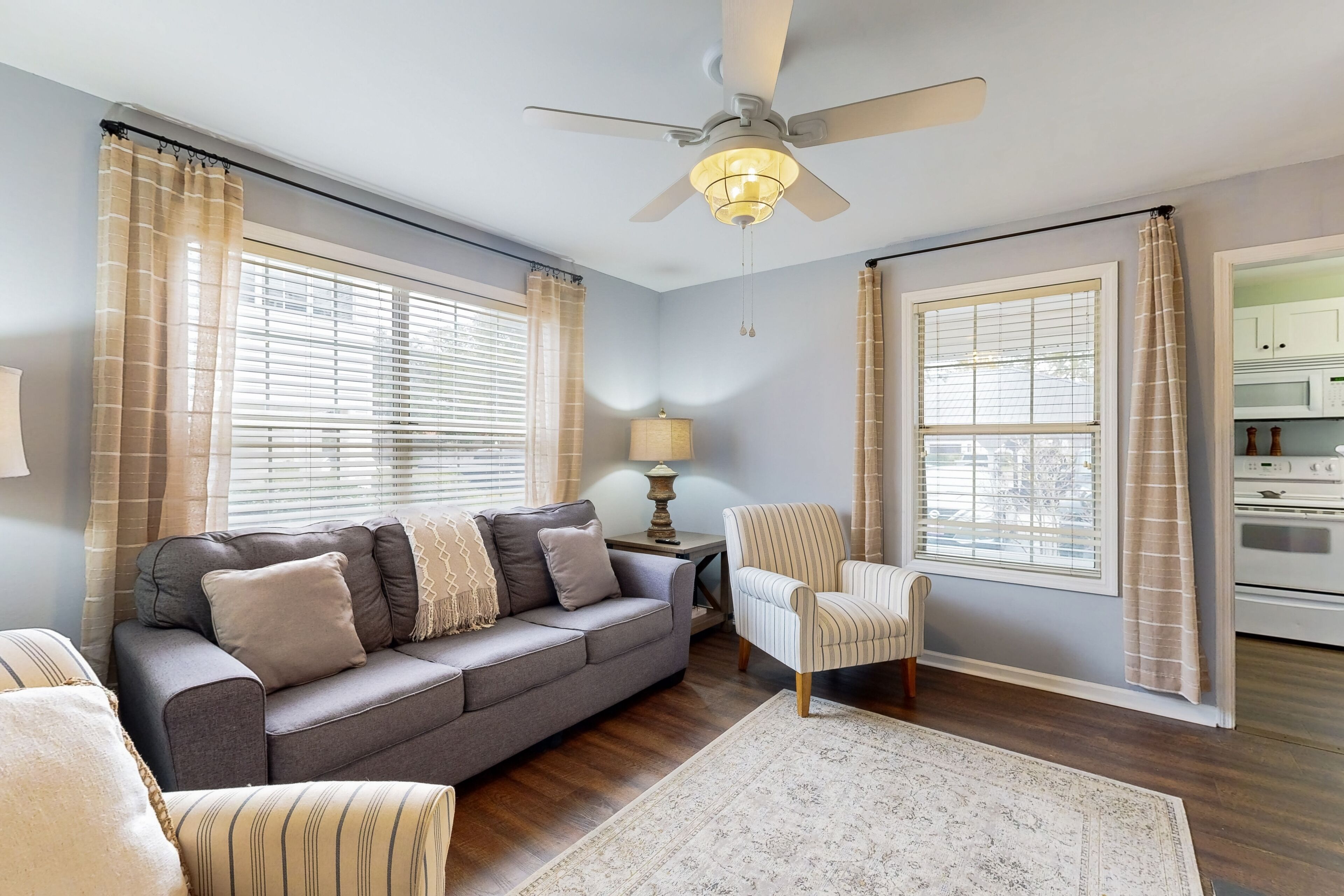 A living room with a grey sofa, striped armchair, and a patterned rug.