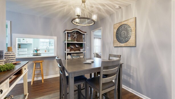 Un coin repas avec une table et des chaises en bois, un lustre et un élément décoratif mural.