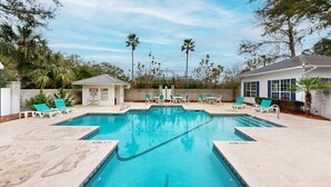 Une piscine rectangulaire à l’eau d’un bleu cristallin, entourée de chaises longues et d’un petit pavillon.