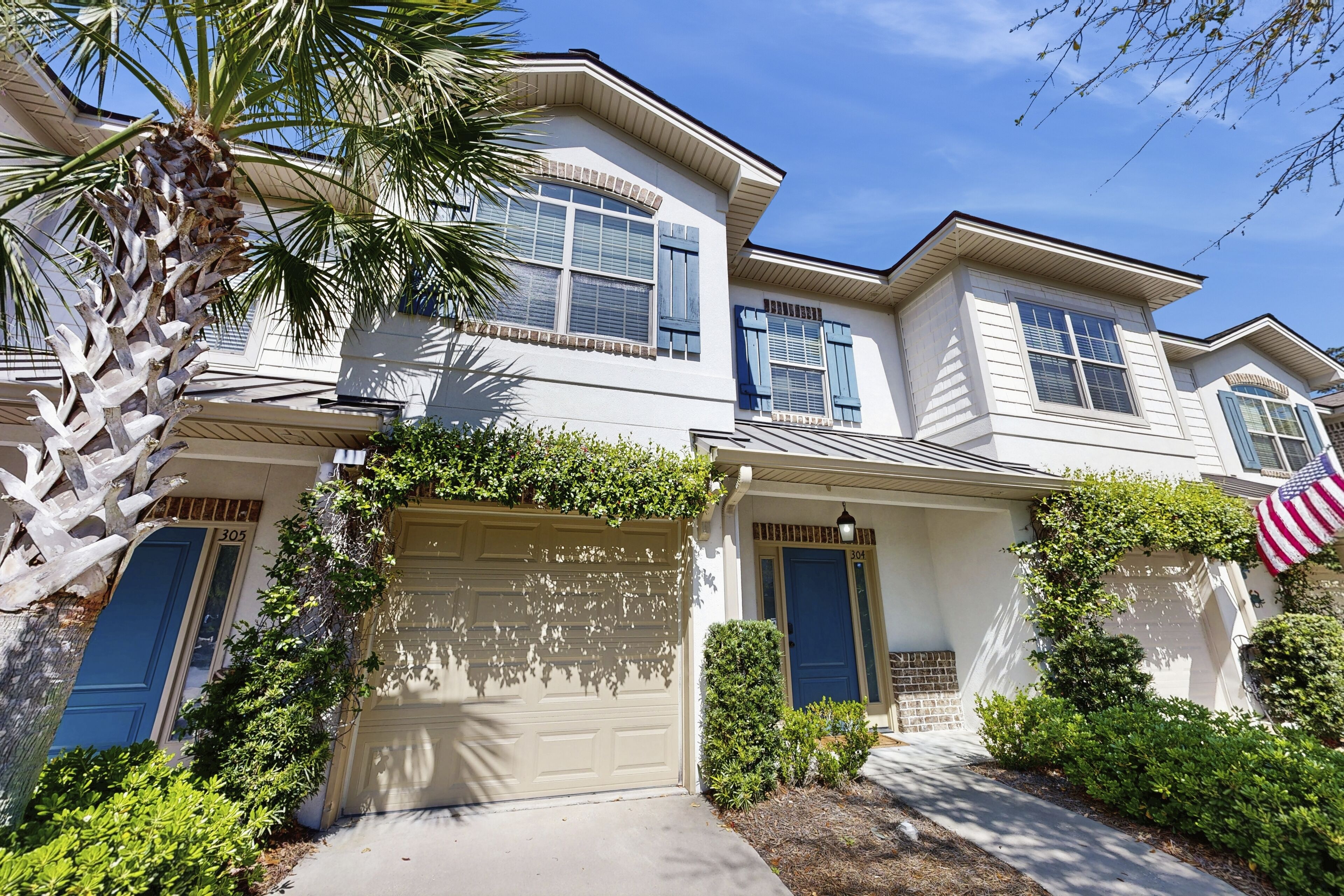 A two-story house with a garage, a front door, and an American flag.