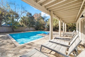 A swimming pool with lounge chairs under a pergola, surrounded by a wooden fence and trees. - Private Pool, LSV/Golf Cart, Bikes, & 2 Kitchens! Easy Walk to Beach! Pet Friendly (Santa Rosa Beach)
