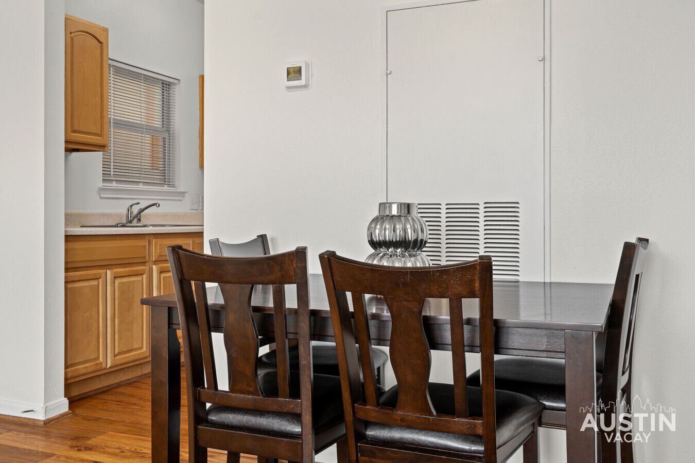 A dining area with a table, chairs, and a window with blinds.