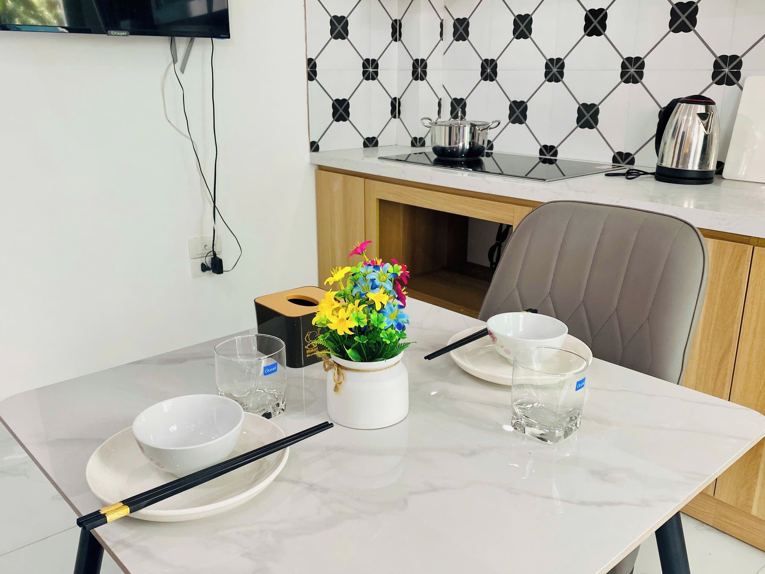 A dining table with a vase of flowers, chopsticks, and bowls.
