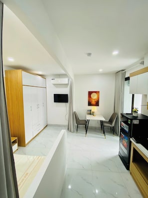 Una cocina moderna con armarios blancos, una mesa de comedor con sillas, un refrigerador y un televisor de pantalla plana montado en la pared.