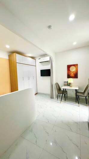 A modern room with a dining area, a TV mounted on the wall, and an air conditioning unit. - 25 House 298 Ngoc Lam - Long Bien bridge (Long Biên)