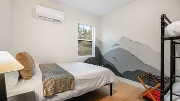 Une chambre avec un lit, une fenêtre, un climatiseur fixé au mur et un lit superposé.