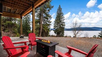 Un espace extérieur aménagé avec des sièges, abrité par un toit, comprenant des fauteuils Adirondack rouges et un foyer noir.