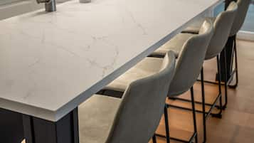 A kitchen with a marble countertop, a sink, and a modern chair design.