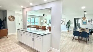 A modern kitchen with white cabinetry, a marble countertop, and a large island. - Palm Villa - 4 Bed, 2.5 Bath, Heated Pool, Hot Tub, Blocks to Beach, Sleeps 10+ (Satellite Beach)