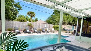 Un jardin avec une piscine, des chaises longues et un jacuzzi.