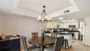 A modern kitchen with white cabinets, a central island, and a dining area with a round table and chairs. - Bright & Modern 3BR House • Steps to Old Town Scottsdale (Scottsdale)