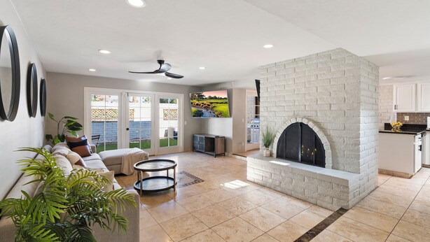 A spacious living area with a fireplace, a sofa, and a television. - Bright & Modern 3BR House • Steps to Old Town Scottsdale (Scottsdale)
