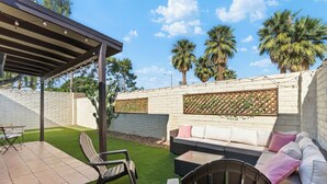 A patio area with a covered seating area, a small table, and chairs. - Bright & Modern 3BR House • Steps to Old Town Scottsdale (Scottsdale)