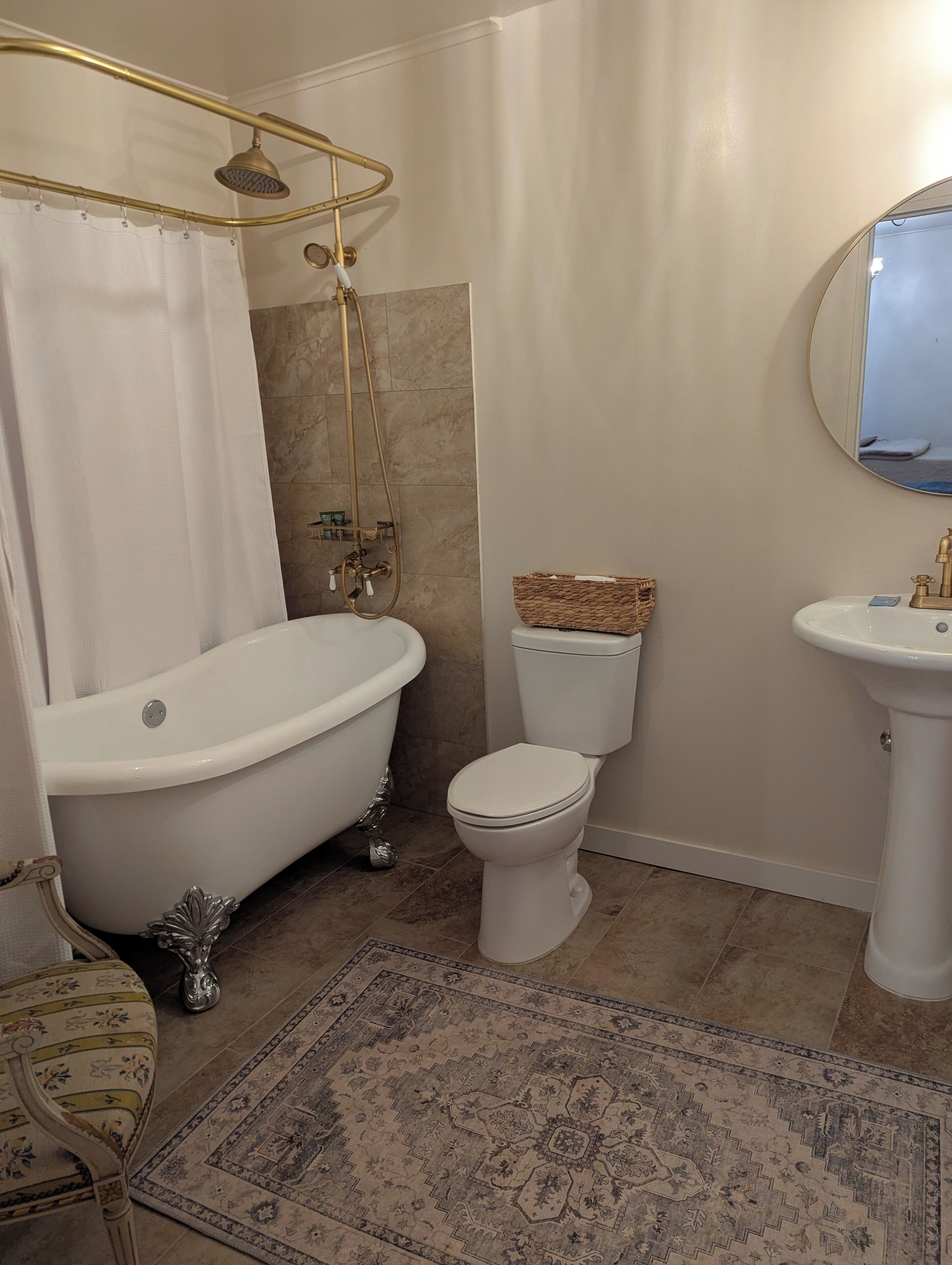 A bathroom with a freestanding bathtub, a toilet, and a pedestal sink.