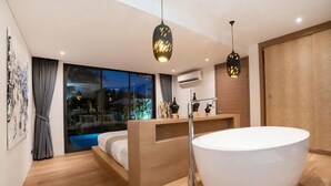 Un baño moderno con una bañera grande, piso de madera y vistas al exterior.
