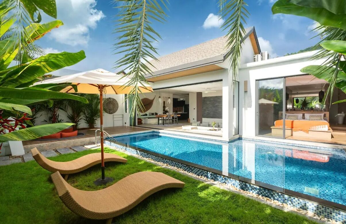 A modern house with a swimming pool, outdoor seating, and lush greenery.