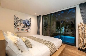 A bedroom with a large bed, a painting on the wall, and a sliding glass door leading to a pool area. - 2BR Pool Villa Near the Sea V261 (Sa Khu)