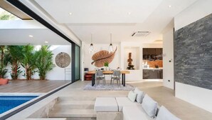 Una sala de estar moderna con piscina, comedor y cocina.