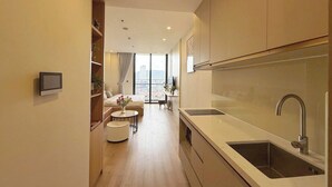 A modern kitchen with a large sink and a dining area with a round table and chairs. - Icon 40 Villa (Bai Chay)
