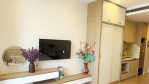 A modern living room with a flat-screen TV, a round mirror, a wooden console table, and a vase with flowers. - Icon 40 Villa (Bai Chay)