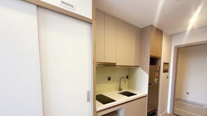 A modern kitchen with white cabinets, a black countertop, and a built-in sink. - Icon 40 Villa (Bai Chay)