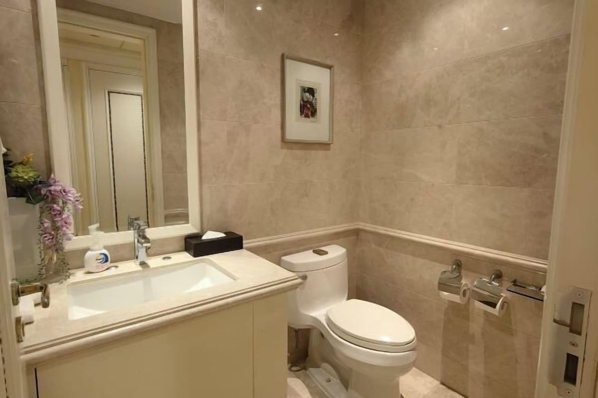 A bathroom with a sink, toilet, and a framed picture on the wall.