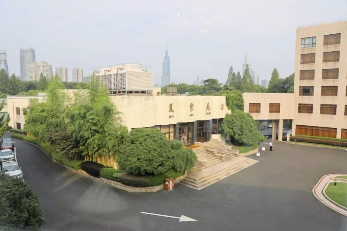A building with a central courtyard, surrounded by trees and a parking area.