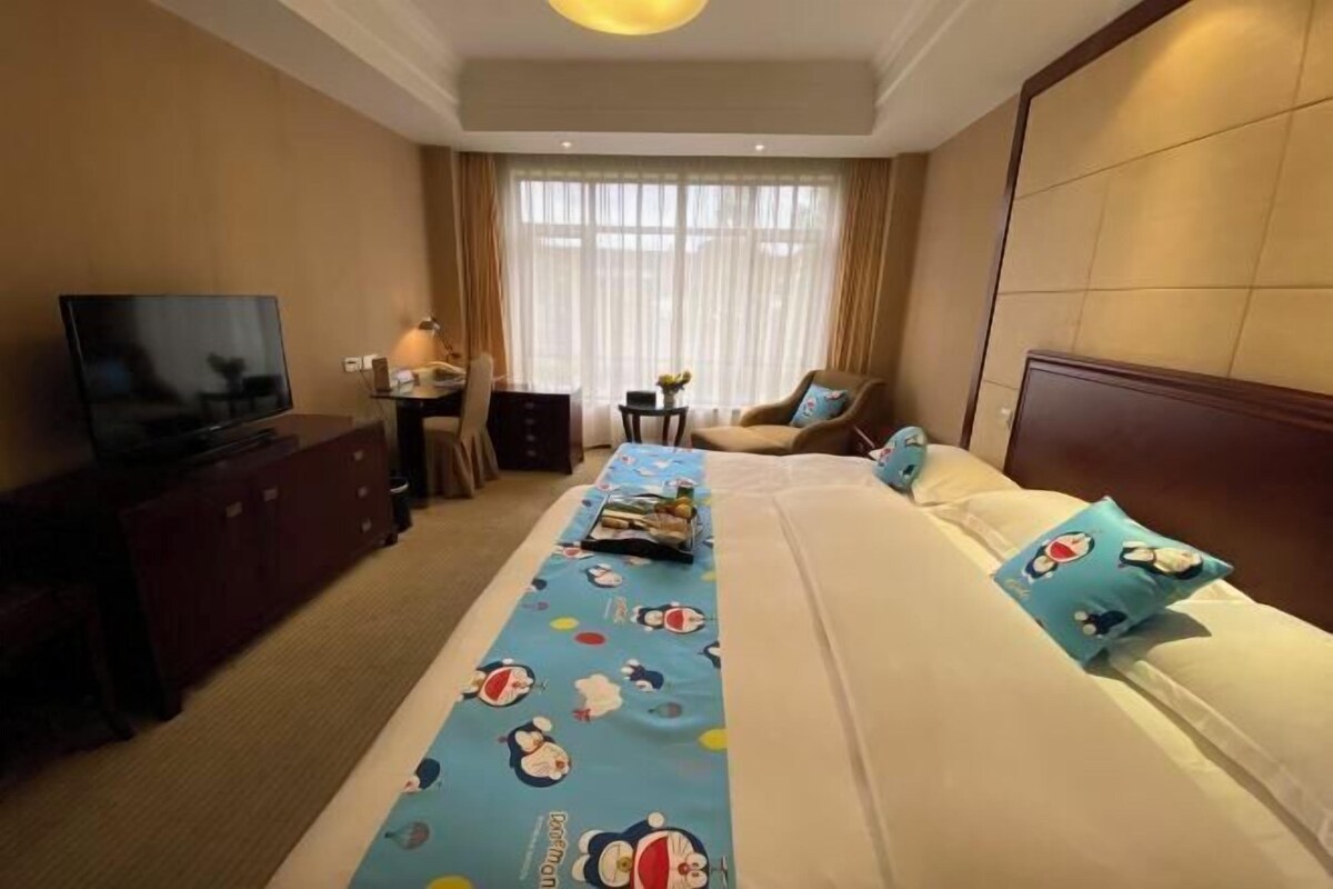 A hotel room with a bed, a television, a desk, and a chair.