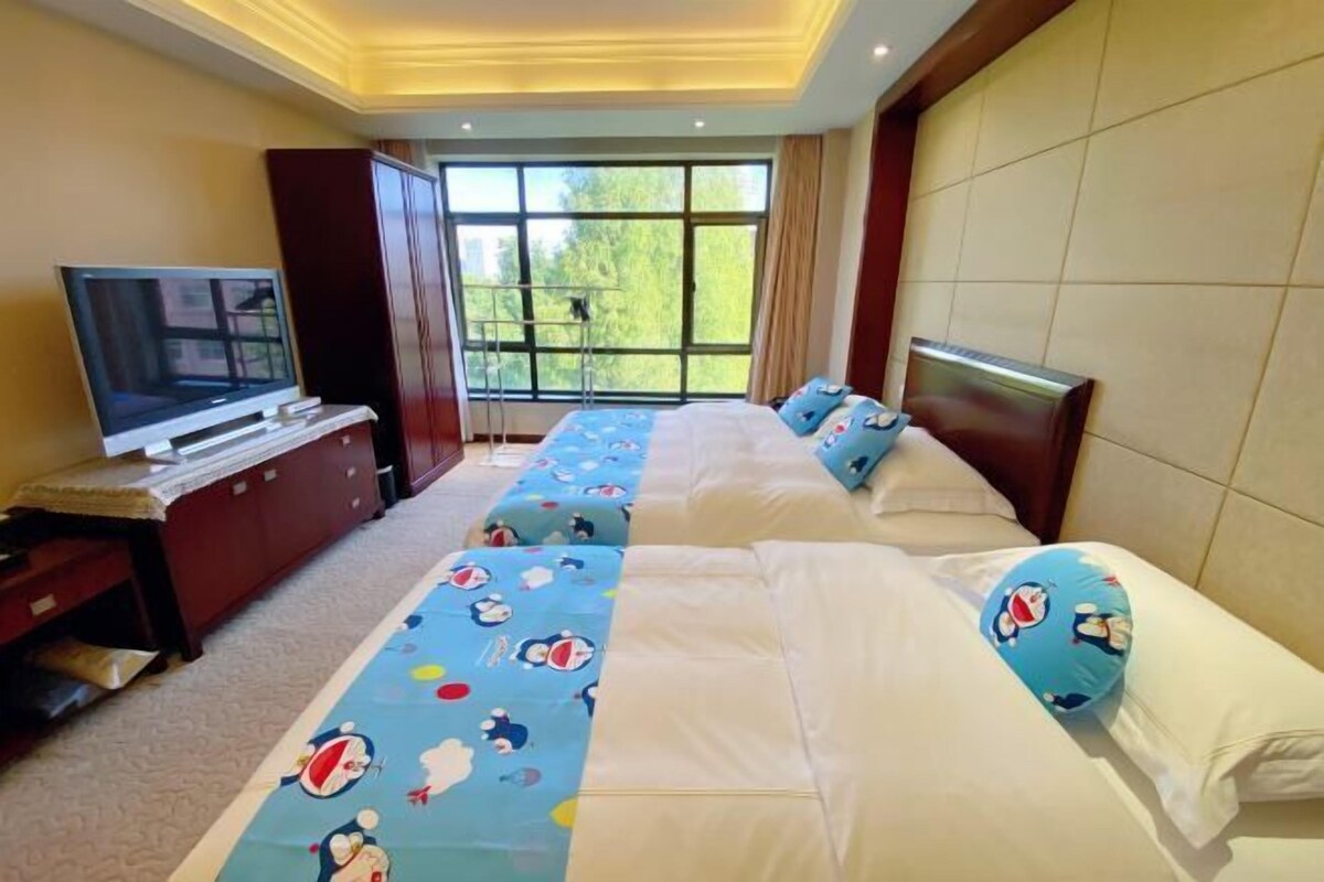 A hotel room with two beds, a TV, and a large window.