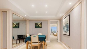 Une chambre d’hôtel avec un coin repas, un grand miroir et des œuvres d’art accrochées aux murs.
