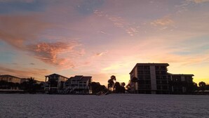 A beachfront property with multiple buildings, including a prominent hotel with a balcony and a pool area. - Boutique Beach Escape in Indian Rocks Beach - 150 steps to the sand (Indian Rocks Beach)
