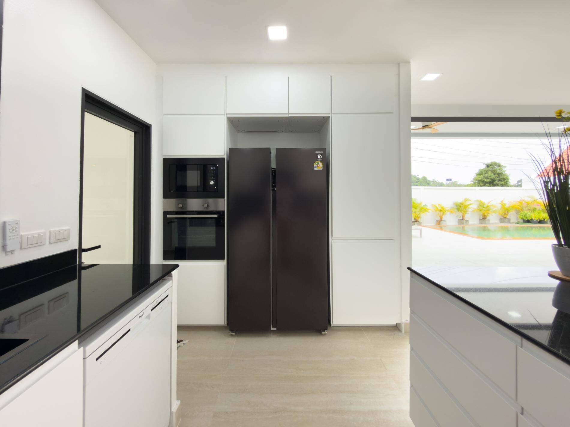 A modern kitchen with a black refrigerator, built-in oven, and microwave.